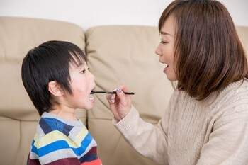 母親が子どもの歯磨きを行っている家族写真