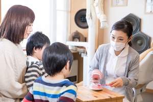歯科医院で歯磨き指導を受けている家族写真